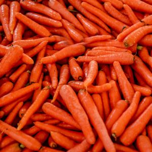A close-up view of a pile of fresh orange carrots, showcasing their vibrant color and texture.